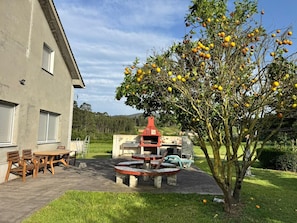 Un edificio con patio, mobiliario exterior y un árbol lleno de frutos.