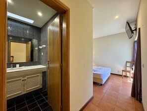 A bathroom with a tiled wall, a wooden door, a mirror, and a sink. - Albufeira Balaia Villa 2 by Homing (Albufeira)