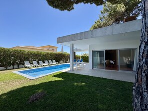 A modern house with a swimming pool, lounge chairs, and a dining area with glass doors. - Albufeira Balaia Villa 2 by Homing (Albufeira)