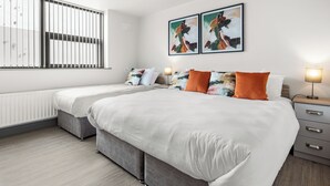 Una habitación de hotel moderna con una cama grande, dos mesitas de noche, un radiador y una obra de arte en la pared.