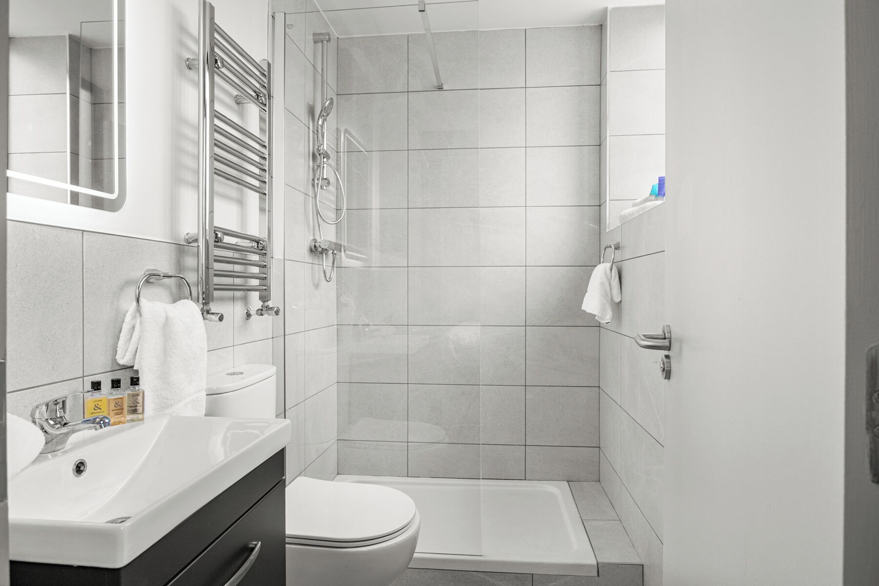 A modern bathroom with a shower, toilet, and sink.