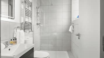 A modern bathroom with a shower, toilet, and sink.
