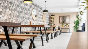 Un interior moderno con bancos de madera, un papel tapiz estampado e iluminación colgante.
