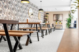 Un interior moderno con bancos de madera, un papel tapiz estampado e iluminación colgante.