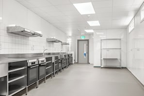 Una cocina moderna con electrodomésticos de acero inoxidable, paredes de azulejos blancos y una distribución limpia y ordenada.