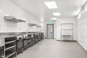 Una cocina moderna con electrodomésticos de acero inoxidable, paredes de azulejos blancos y una distribución limpia y ordenada.