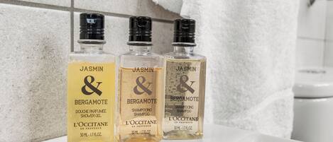 Drei Flaschen JASMIN & BERGAMOTE Shampoo auf einer Badezimmerablage.