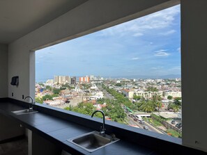 Eine Küche mit einem großen Fenster und Blick auf eine Stadtlandschaft.