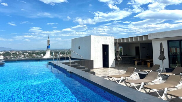 A rooftop pool with lounge chairs and a view of a cityscape and mountains in the distance. - Condo with excellent views 10 minutes from the boardwalk Super equipped (Puerto Vallarta)