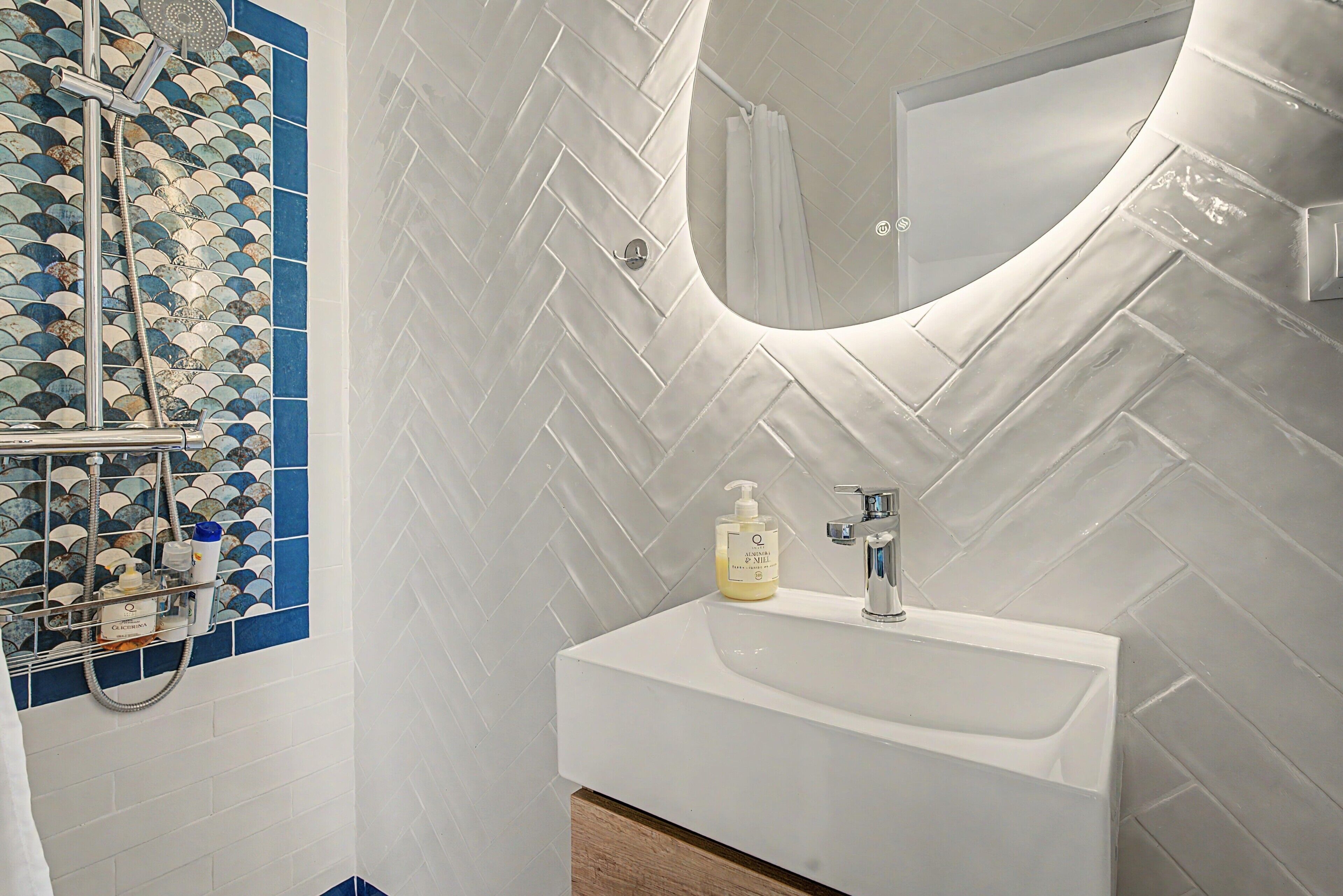 Une salle de bain avec un lavabo blanc, un miroir et un espace douche.