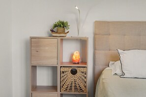 Une table de chevet en bois, agrémentée d’un panier tressé, d’une pierre chauffante et d’une plante en pot.