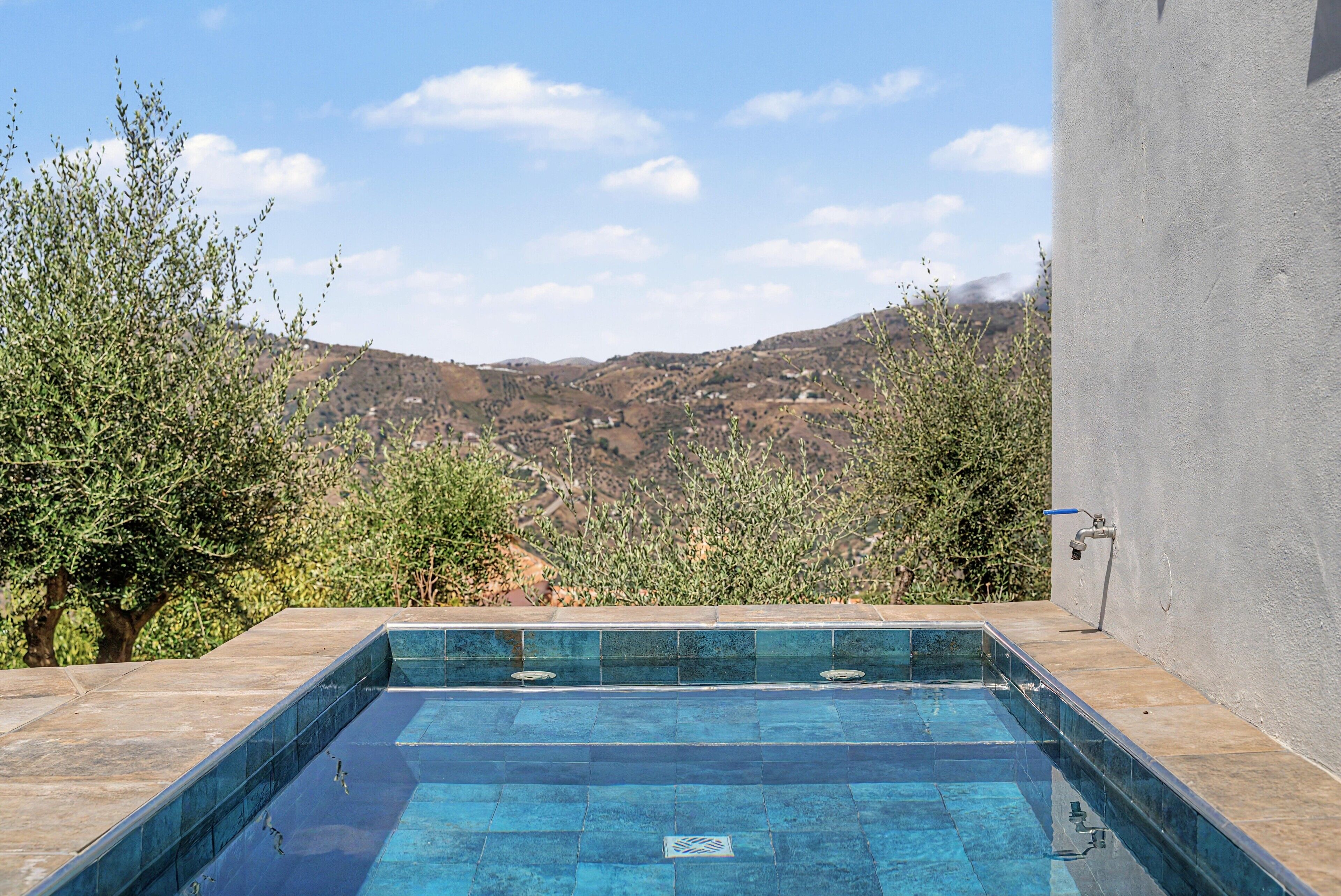 A rectangular swimming pool with a view of a mountainous landscape.