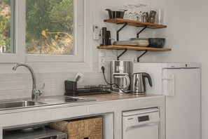 A modern kitchen with a built-in dishwasher, a coffee maker, and a kettle on the counter. - The View – Villa with Private Pool, Walking Distance to Cómpeta (Cómpeta)