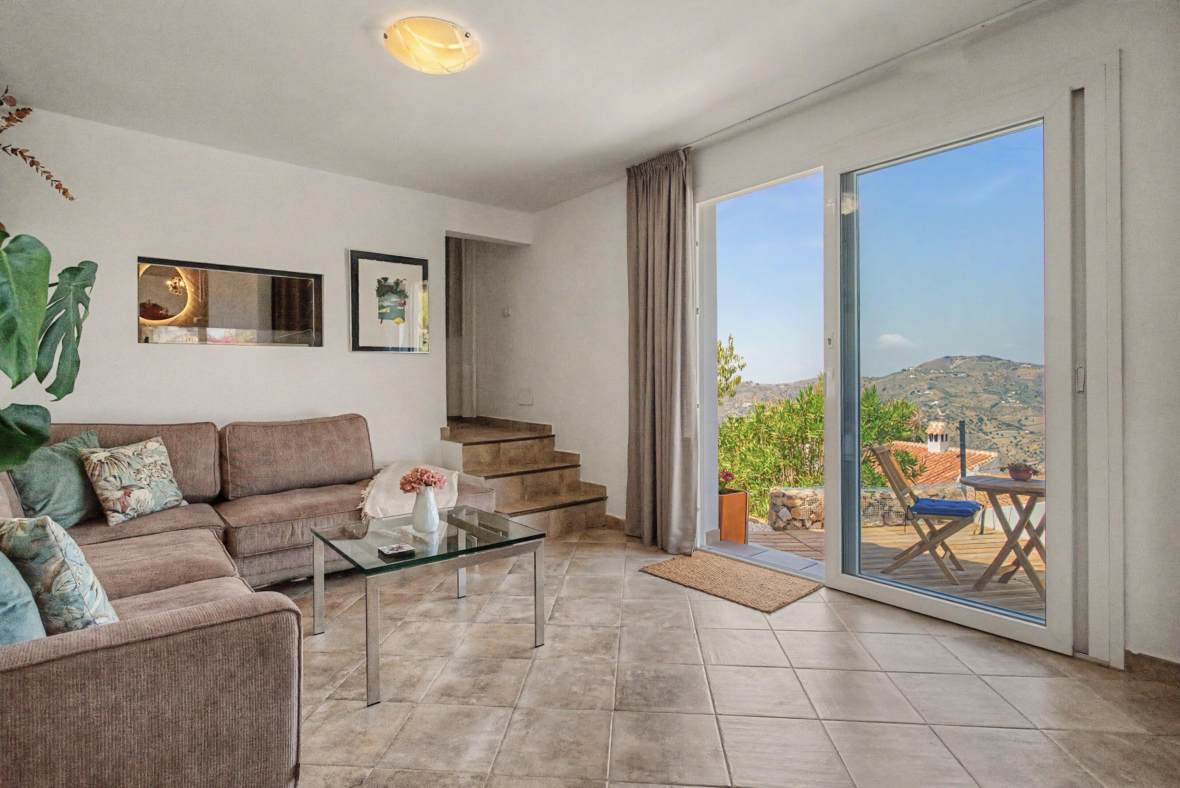 Un salon comprenant un canapé, une table basse et donnant sur un balcon aménagé avec du mobilier d’extérieur.