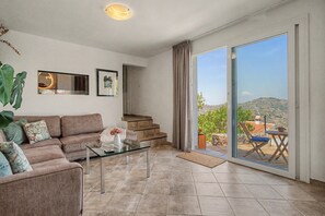A living room with a sofa, a coffee table, and a view of a balcony with outdoor furniture. - The View – Villa with Private Pool, Walking Distance to Cómpeta (Cómpeta)
