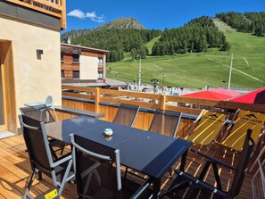 An outdoor deck with a table and chairs, overlooking a mountainous landscape.