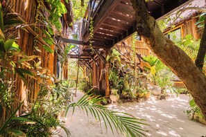 A covered outdoor area with wooden beams and lush greenery. - Oceanfront Getaways Start Here Pool, Jacuzzi & Gym (Tulum)