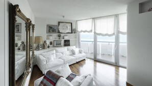 Un salon spacieux avec un canapé blanc, un grand miroir et un balcon offrant une vue dégagée.