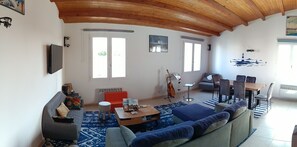 A living room with a sofa, a coffee table, a dining table with chairs, a guitar, and a painting on the wall. - Apartment in the heart of the village of Saint-Denis-d'Oléron. (Saint-Denis-d'Oléron)