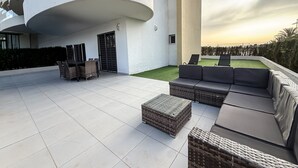 A modern outdoor patio with a dining set, lounge area, and a view of the sunset. - Apartment 'Bahia' with Shared Pool, Wi-Fi and Air Conditioning (Els Arenals del Sol)