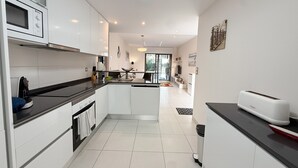 A modern kitchen with white cabinets, a microwave, a stove, and a toaster. - Apartment 'Bahia' with Shared Pool, Wi-Fi and Air Conditioning (Els Arenals del Sol)