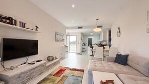 A modern living room with a flat-screen TV, a sofa, a coffee table, and a colorful rug. - Apartment 'Bahia' with Shared Pool, Wi-Fi and Air Conditioning (Els Arenals del Sol)
