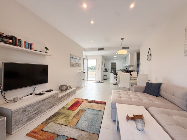 A modern living room with a flat-screen TV, a sofa, a coffee table, and a colorful rug.