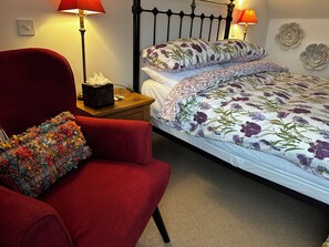 A bedroom with a single bed, a red armchair, a wooden nightstand, and two wall-mounted lamps. - Charming 2-bedroom cottage in Inverness perfect for relaxing stays (Inverness)