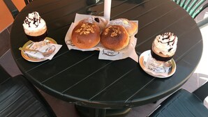 Pyöreä pöytä, jonka päällä on kolme leivosta ja lasi tummaa juomaa.