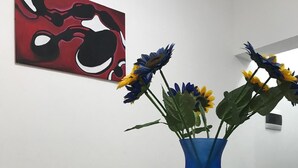 Ruokapöytä, jonka päällä on sininen maljakko, jossa on kukkia, sekä kaksi vihreää hedelmää.
