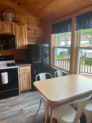 Eine Küche mit Holzausstattung, einem Kühlschrank, einem Herd und einem Esstisch mit Stühlen.