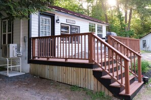 Eine kleine Holzhütte mit einer Holzterrasse und einer Treppe zu einer überdachten Veranda.