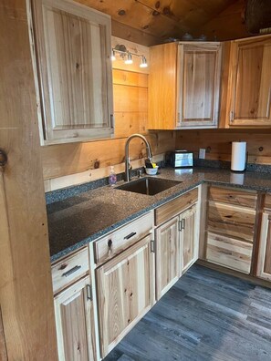 Eine Küche mit Holzausstattung, einer Arbeitsplatte aus Granit, einer Spüle aus Edelstahl und einem eingebauten Backofen.