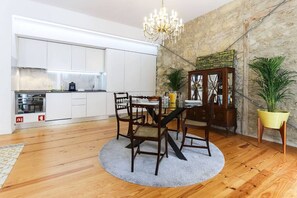 A modern kitchen with white cabinets, a dining area with a round table and chairs, and a chandelier. - Azzulea Avenida21 Historic Charm, Modern Luxury (Lisbon)