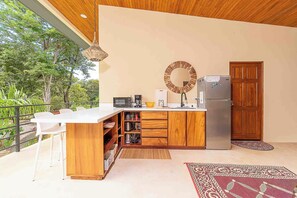 Eine moderne Küche mit einer Holztischinsel, weißen Barhocker, einer eingebauten Mikrowelle und einem Kühlschrank.