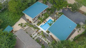 A two-story building with a swimming pool, surrounded by greenery and a paved area. - Walk to beach, 2BR/2BA, Apartment, pool, parking, outdoor kitchen (Playa Grande)