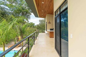 Ein moderner Balkon mit Pool, Holzboden und Essbereich mit Barhocker.