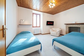 Una habitación con dos camas, chimenea, televisión y ventana.