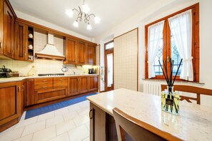 Una cocina con armarios de madera, encimera de mármol y ventana con cortinas.