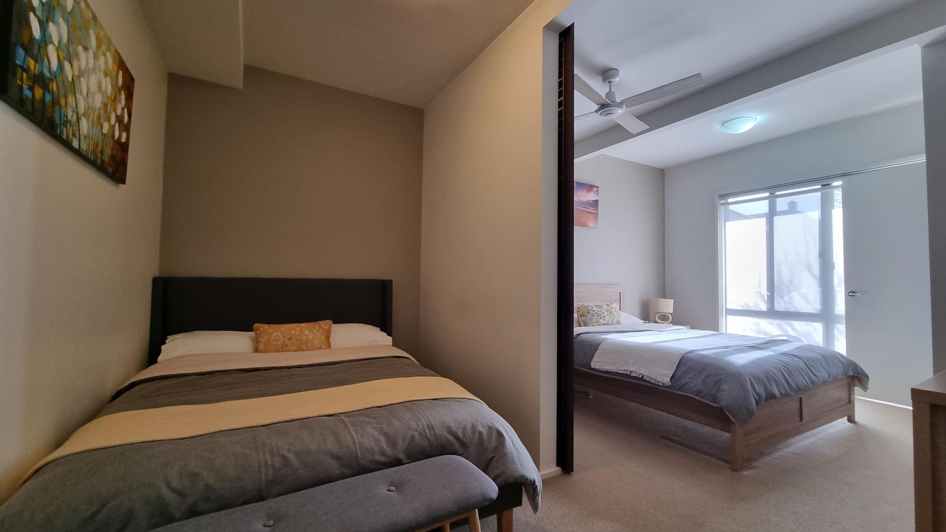 Ein Schlafzimmer mit zwei Betten, einem Deckenventilator und einem Fenster.