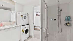 Un bagno moderno con box doccia in vetro, lavatrice e WC.