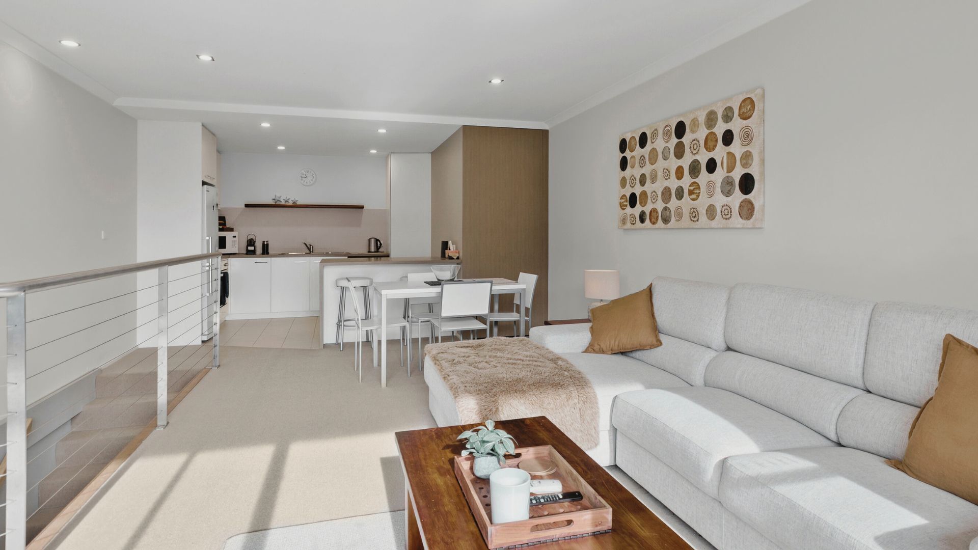 A modern living room with a sofa, coffee table, and a dining area with chairs and a table.