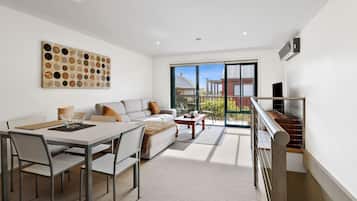 A modern living room with a dining area, a large window with a view, and a staircase.