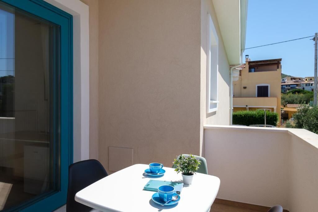 Een balkon met een tafel gedekt voor twee personen, een plant in pot en uitzicht op omliggende gebouwen.