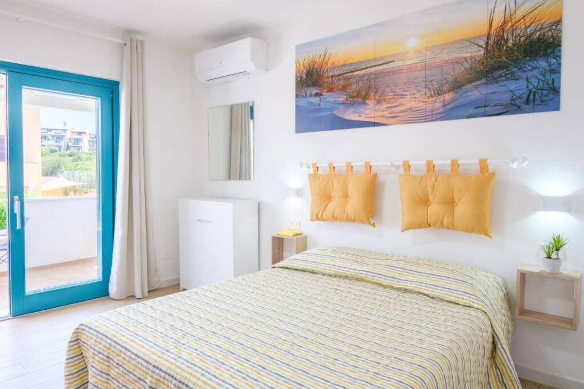 Un dormitorio con cama, un cuadro, una ventana y una puerta.