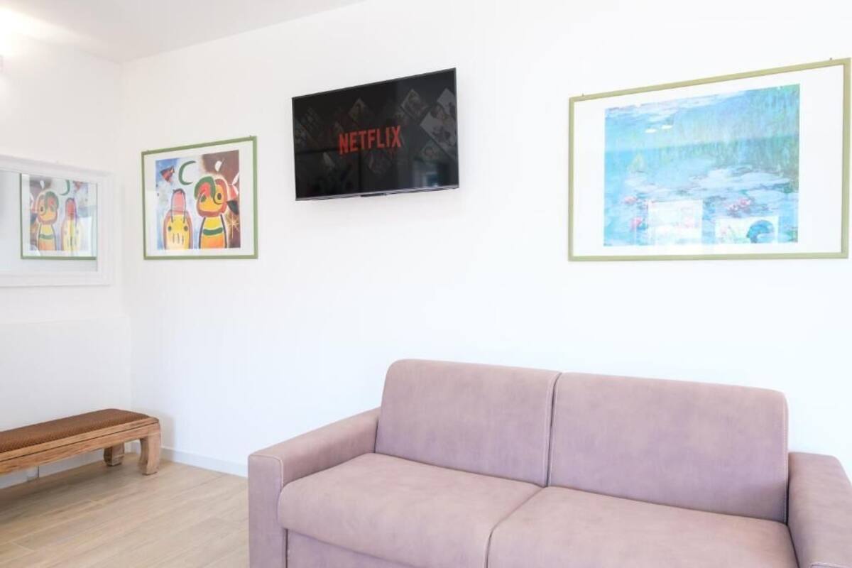 Una habitación con sofá, banco y obras de arte enmarcadas en la pared.