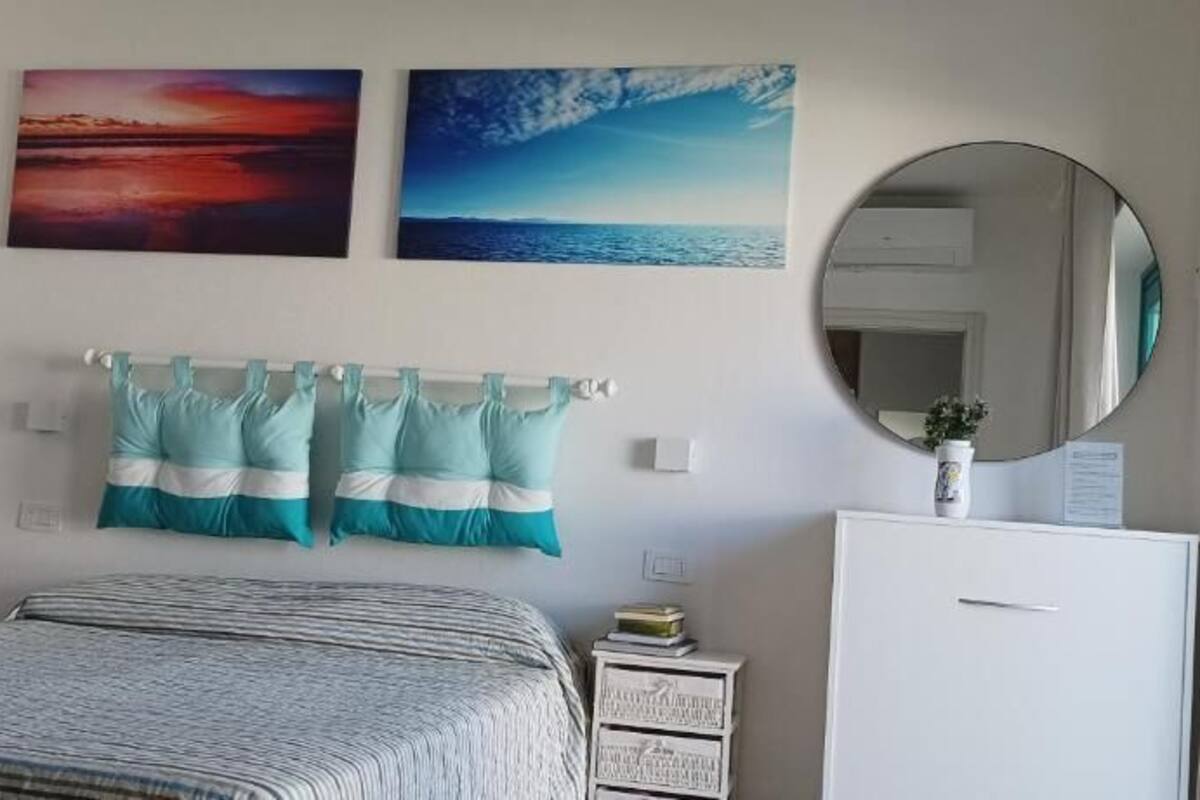 Un dormitorio con una cama, un tocador, un espejo y dos cuadros en la pared.