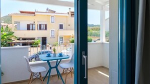 Uma varanda com mesa e cadeiras, vista para um edifício amarelo e uma porta que dá para uma área externa.