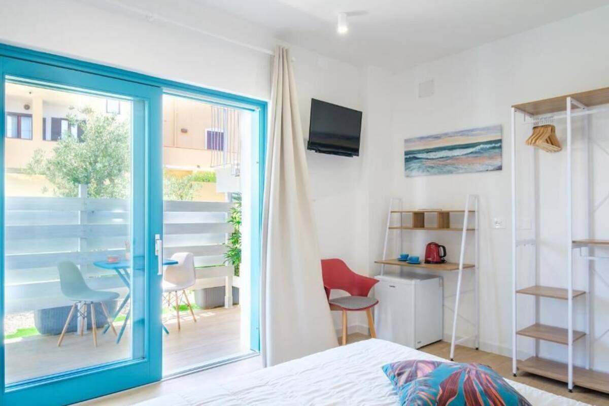 Habitación con cama, escritorio, silla, televisor y vistas al exterior.