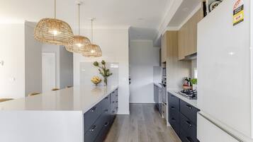 A modern kitchen with a central island, grey cabinetry, and a hanging light fixture.